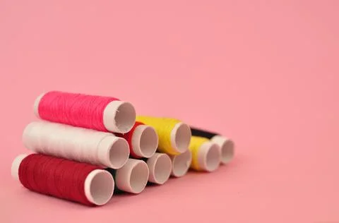 Multicolored threads for sewing on pink background Stock Photos