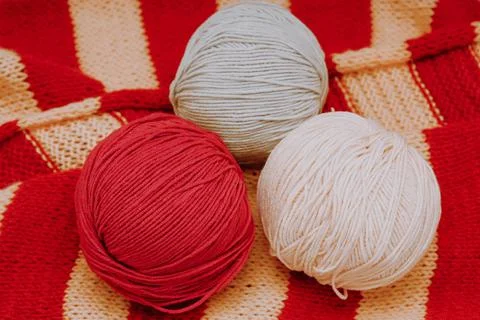 Multicolored three balls of wool lie on a knitted tablecloth Stock Photos