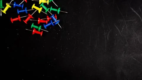Multicolored thumbtacks on a black background Stock Photos