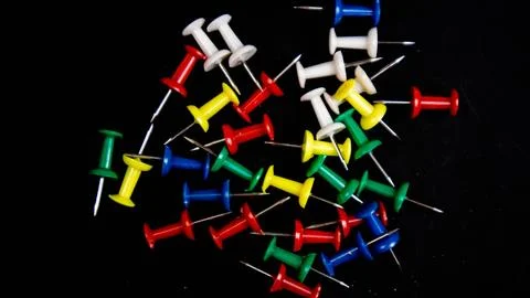 Multicolored thumbtacks on a black background Stock Photos