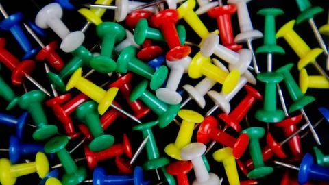 Multicolored thumbtacks on a black background Stock Photos