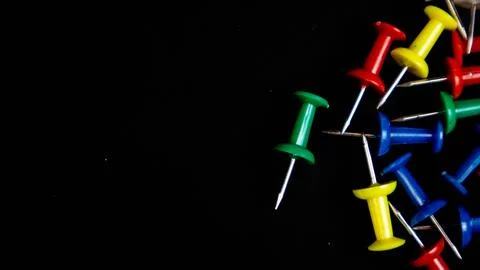 Multicolored thumbtacks on a black background Stock Photos