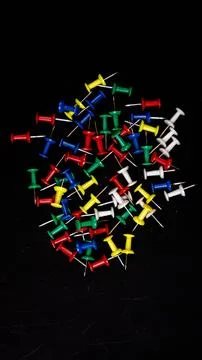 Multicolored thumbtacks on a black background Stock Photos