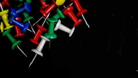 Multicolored thumbtacks on a black background Stock Photos