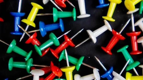 Multicolored thumbtacks on a black background Stock Photos