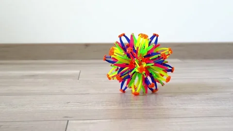 A multicolored toy falls on the floor, when the hand raises it, the ball opens 動画素材 130490759