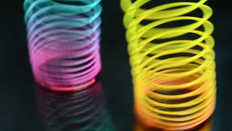 Multicolored toy spring on a dark background. Slinki toy. Stock-Footage 97985466