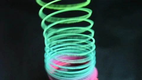 Multicolored toy spring on a dark background. Slinki toy. Video stock 97986423