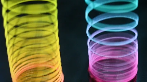 Multicolored toy spring on a dark background. Slinki toy. Stock-Footage 97989656
