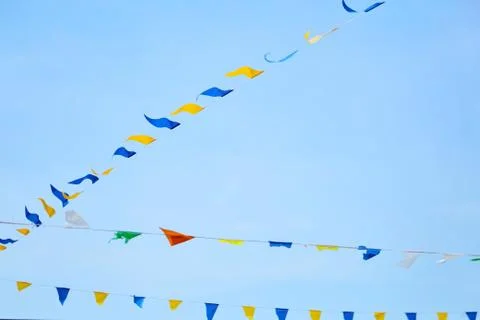 Multicolored triangular festival flags on blue sky background Stock Photos