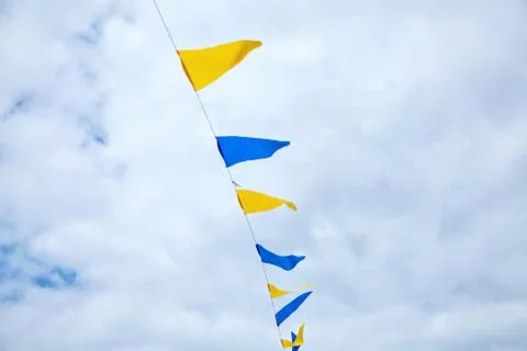 Multicolored triangular festival flags on blue sky background Stock Photos
