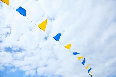 Multicolored triangular festival flags on blue sky background Stock Photos