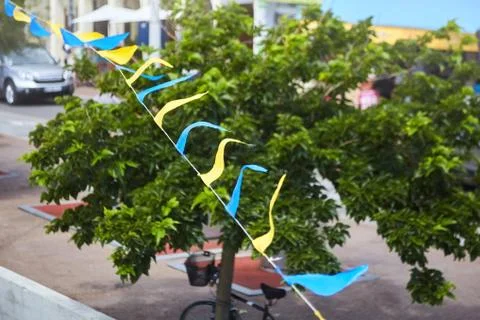 Multicolored triangular festival flags on green trees background Stock Photos