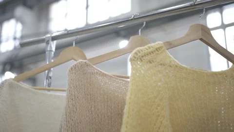 Multicolored wool knitted sweaters hanging from clothes hangers Stock Footage 160125258