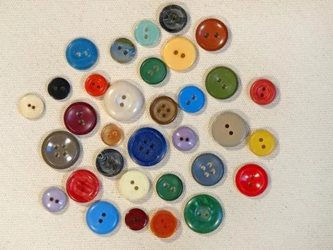 Multicoloured buttons on beige fabric. Stock Photos