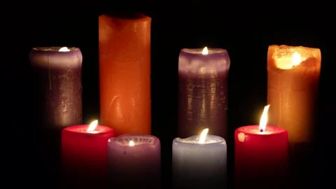 Multicoloured candles burn on a black background. C0185 Stock Footage 255166262