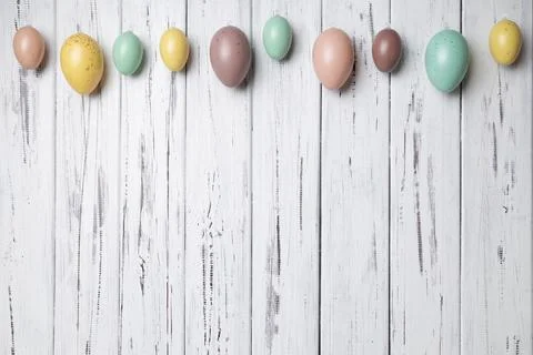 Multicoloured Easter eggs on white vintage aged wooden background. Copy space Stock Photos
