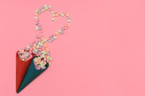Multicoloured marshmallow fell from two waffle cups to pink background. 写真素材