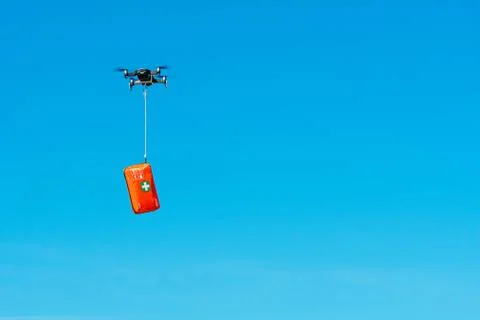 Multicopter drone flying with a first aid kit isolated on a blue sky, emergen Foto stock