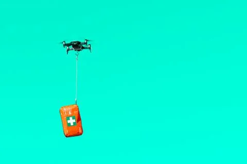 Multicopter drone flying with a first aid kit isolated on a light green backg Stock Photos