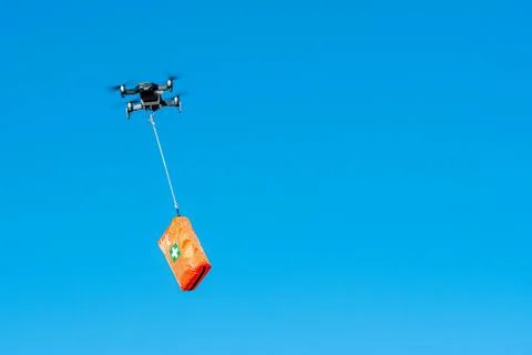Multicopter drone flying with a first aid kit isolated on a blue sky, emergen Foto stock
