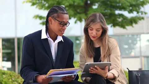 Multicultural Business partners reviewing documents and using tablet outdoor Stock Footage 317014352