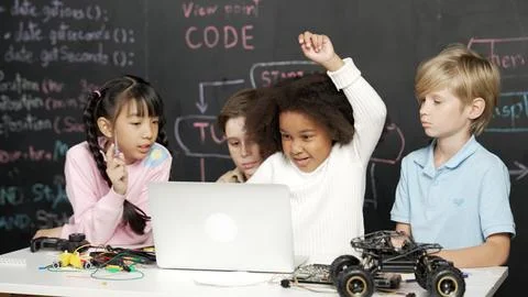 Multicultural children using laptop programing engineering code. Erudition. Foto stock