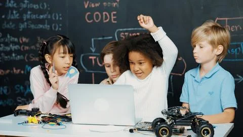 Multicultural children using laptop programing engineering code. Erudition. Stock Photos