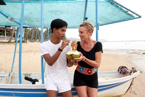 Multicultural couple drinking a natural coconut in a beach Stock Photos