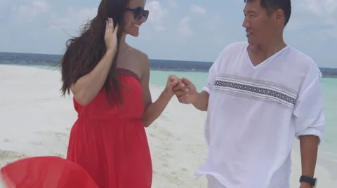 Multicultural Couple Holds Hands Lovingly While Walking Along Romantic Island Stock Footage 45856753