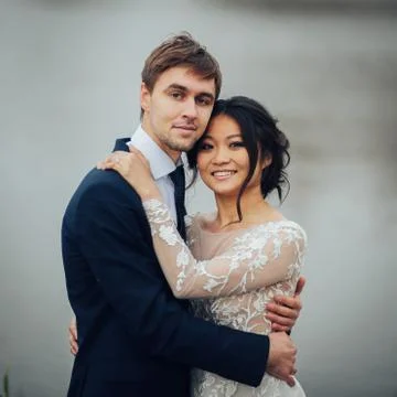 Multicultural couple hugging each other on lake with old castle Stock Photos