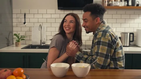 Multicultural couple sitting at the kitchen table enjoying each other's company. Stock Footage 305652332