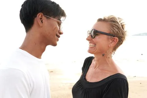 Multicultural couple smiling to each other in a sandybeach Stock Photos