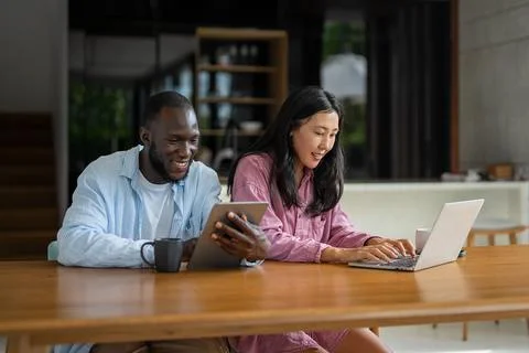 Multicultural couple working remotely, planning finances and investments. D.. Stock Photos