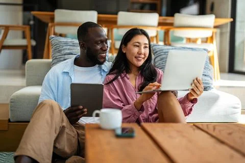Multicultural couple working remotely, planning finances and investments on.. Stock Photos