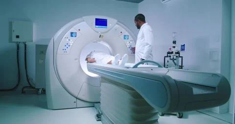 Multicultural doctor is pushing buttons at CT scanner. Patient is finished Stock Footage 243607073
