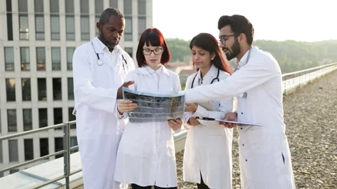 Multicultural doctors discussing patient's CT scan outside the hospital. Stock Footage 262486595