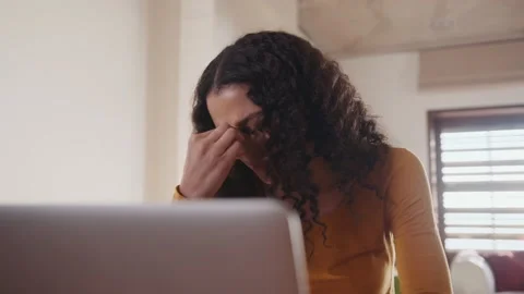 Multicultural female concerned, typing on laptop, working remotely from home at Stock Footage 166940086