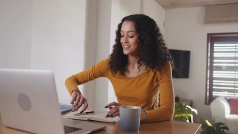Multicultural female smiling, working on laptop and making notes in notepad Stock Footage 169012966