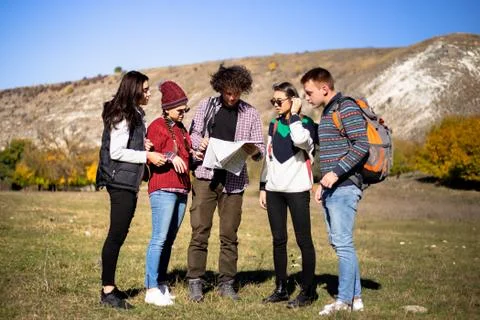 A multicultural friends using a map try to find the right way to next Stock Photos