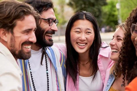 Multicultural group of friends looking at each other smiling while embracing in Stock Photos