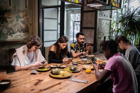 A multicultural group of students sharing a meal in a cafe and u Stock Photos