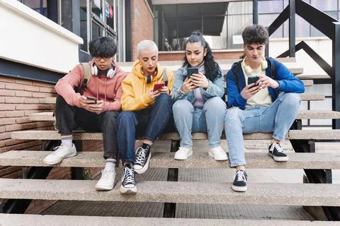Multicultural group of young friends using cellphones and social media - Stock Photos