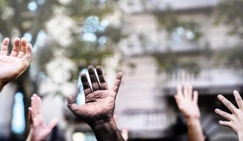 Multicultural hands raised in the air asking for freedom in a demonstration o Stock Photos