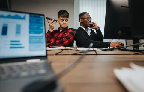 Multicultural office setting with young employees focused on business calls Stock Photos