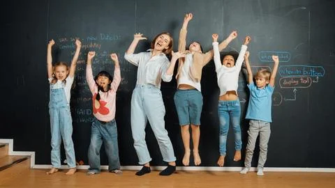 Multicultural student and teacher smiling and standing at blackboard. Erudition. Stock Photos