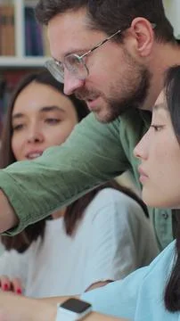 Multicultural students study for exams as a team, use computer, talk, look .. Stock Photos