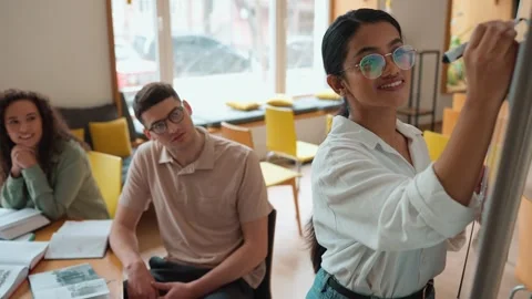 Multicultural students studying and looking at whiteboard in library Stock Footage 250339699