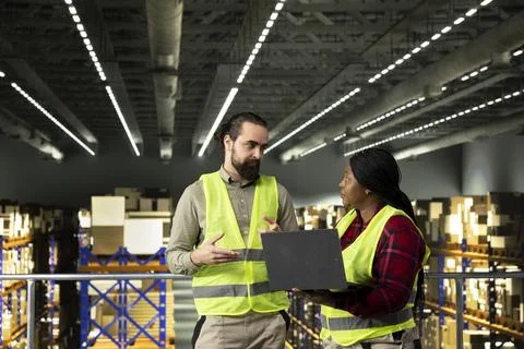 Multicultural team collaborating in industrial warehouse on platform 库存照片