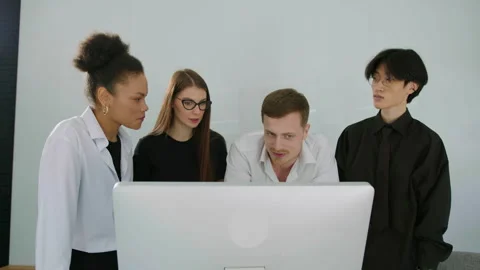 Multicultural team discusses the progress of work looking at computer monitor Stock Footage 246050869